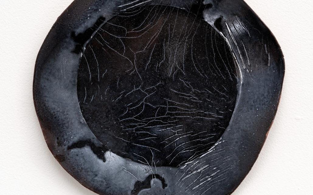 Keramikk av Nina Malterud, tallerkenformet i sorte nyanser.